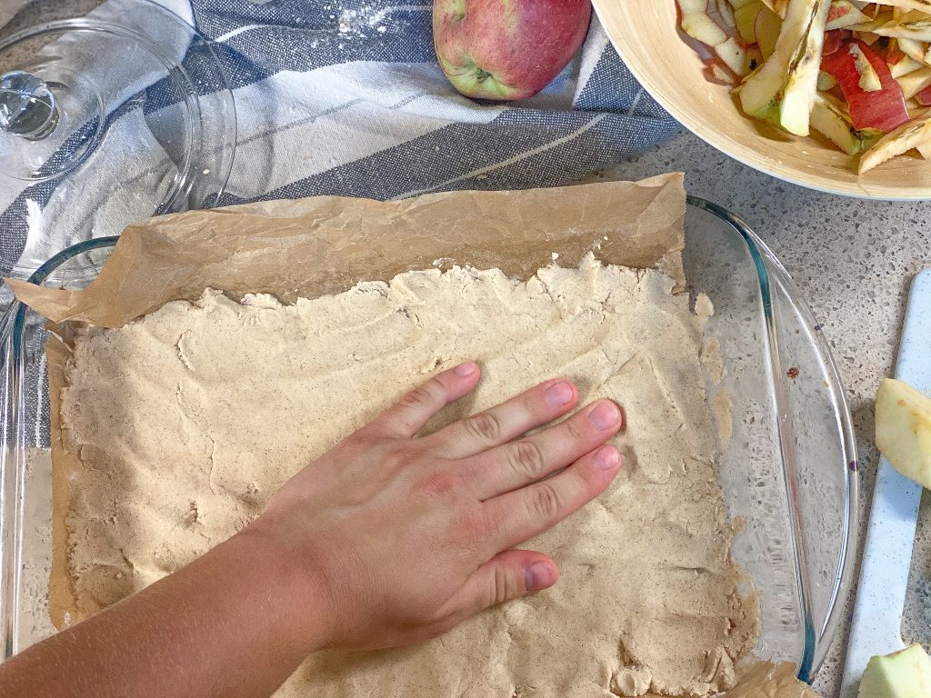 hand pressing down dough into a baking sheet