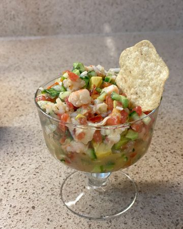 ceviche in a glass bowl with a tortilla chip in it