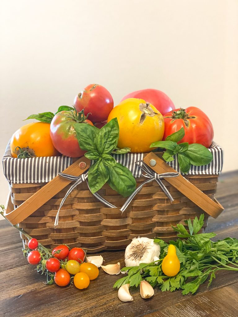 tomato's collected in a basket with fresh herbs and garlic