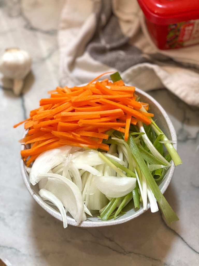 chopped carrots, green onions, and onions in a small white bowl.