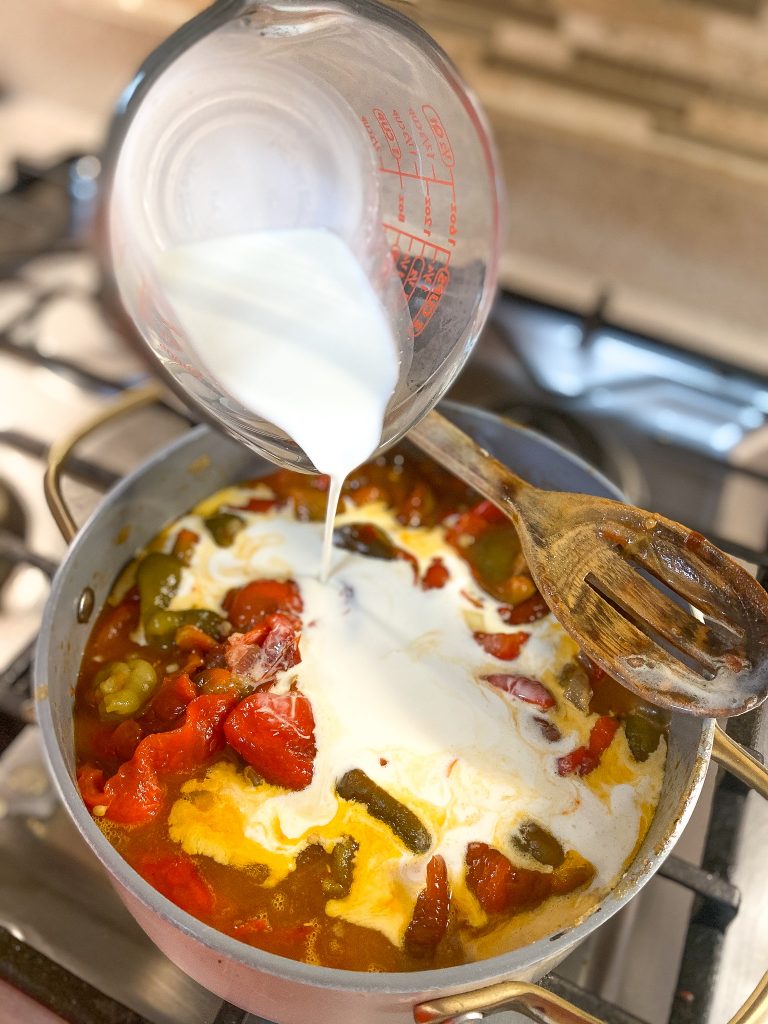 pouring crem into a pot with roasted bell peppers