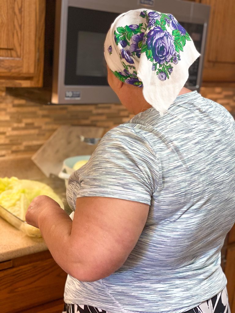 woman cooking cabbage with a white and blue head wrap