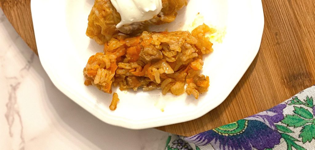 unrolled cabbage roll on a white plate that's on a wooden table top