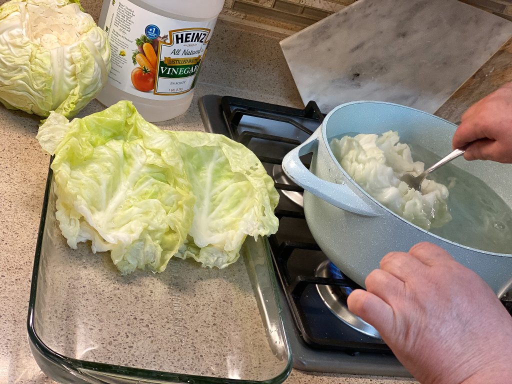 hand cooking cabbage in a pot with water