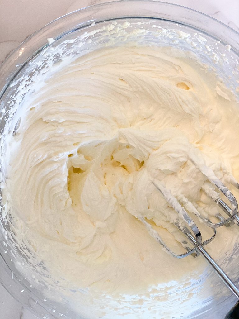 mixier whipping cream cheese in a clear bowl