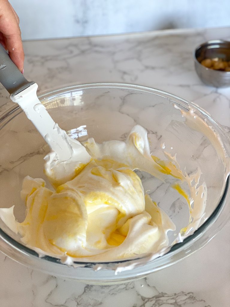 hand folding in egg yolks into white merengue
