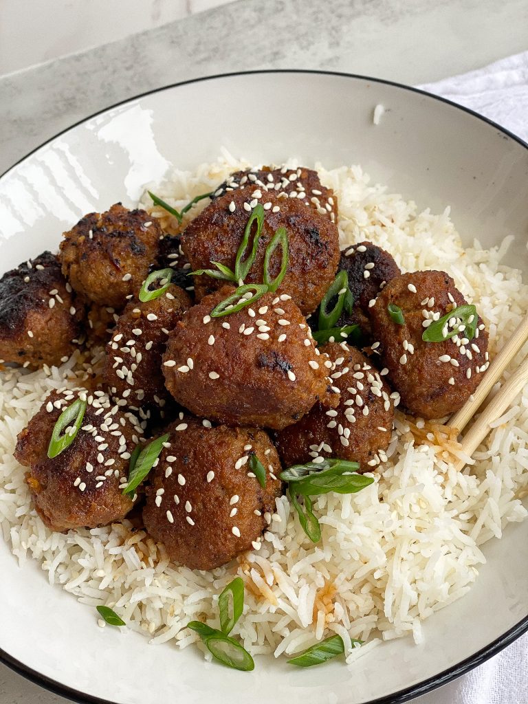 Meatballs with an Asian sticky sauce over rice with spring on top