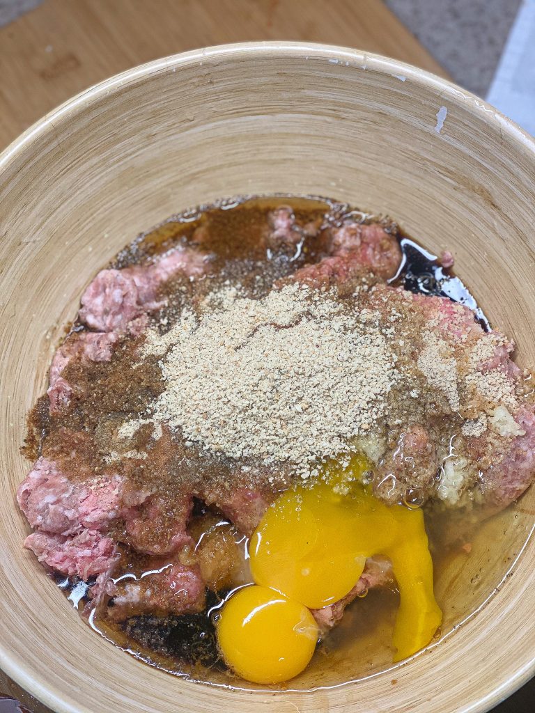in a wooden bowl are ingredients to make Asian pork meatballs