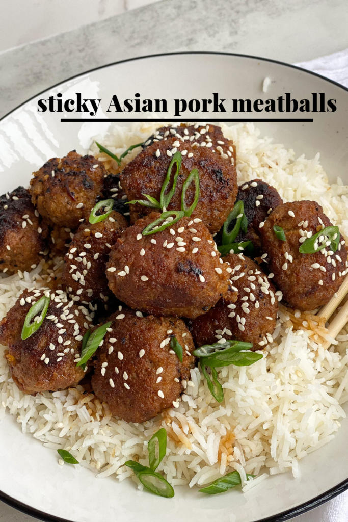 sticky Asian pork meatballs in a white bowl with rice and spring onions on top with sesame seeds