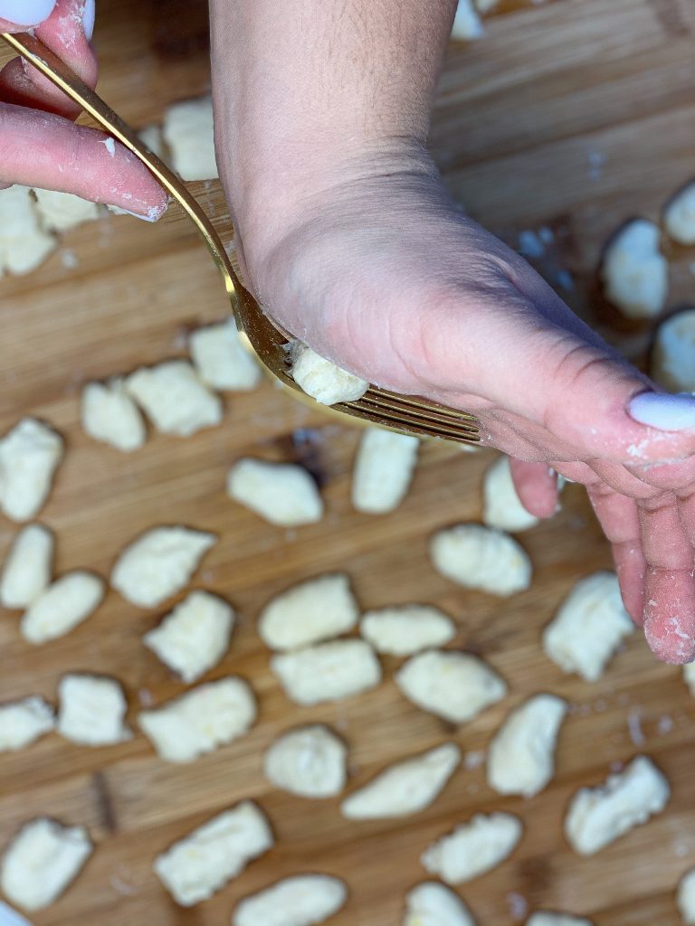 hand rolling gnocchi on a fork to make the imprints