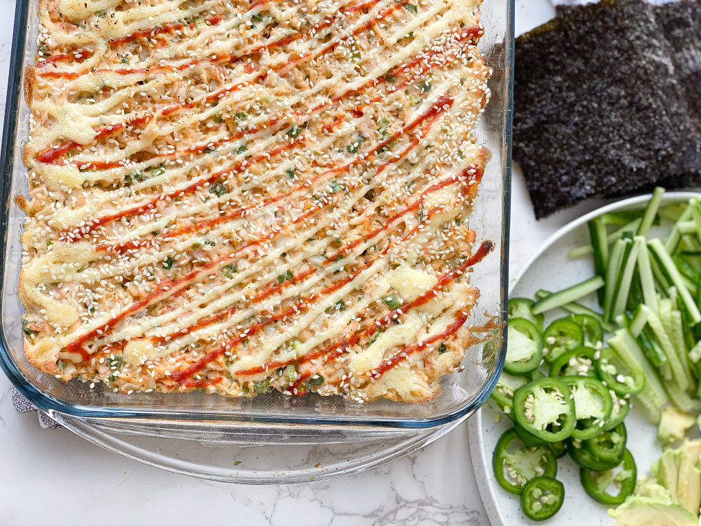Easy sushi bake in a casserole dish with seaweed next to it ad fresh cut jalapenos on the side