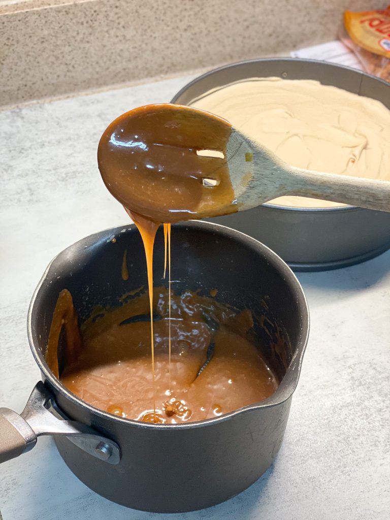 caramel cookie butter mixture in a saucepan with a wooden spoon
