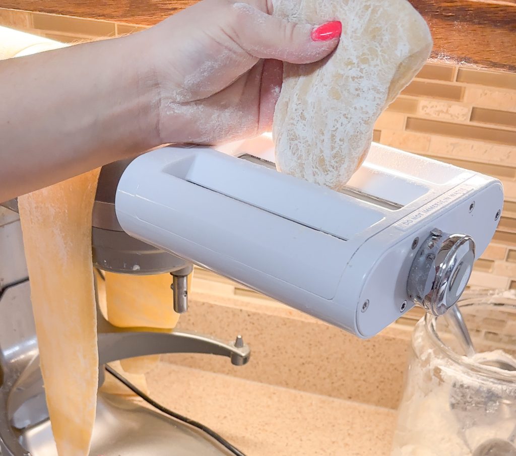 hand feeding pasta through the pasta maker machine