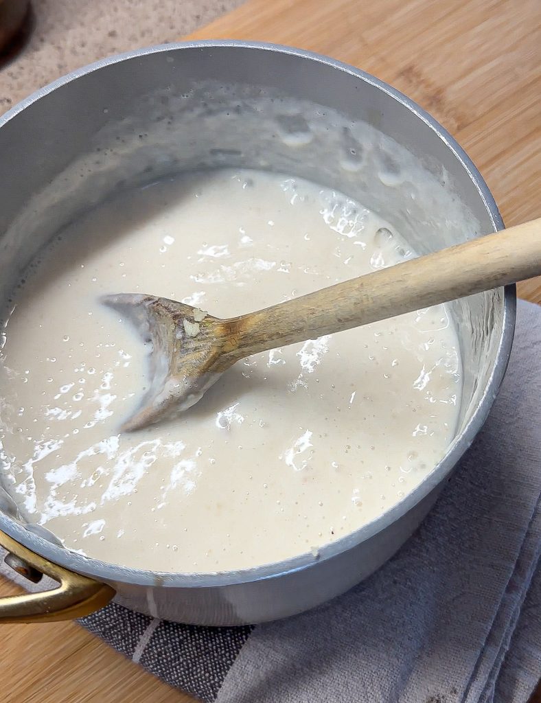 bechamel sauce in a pot with a wooden spoon