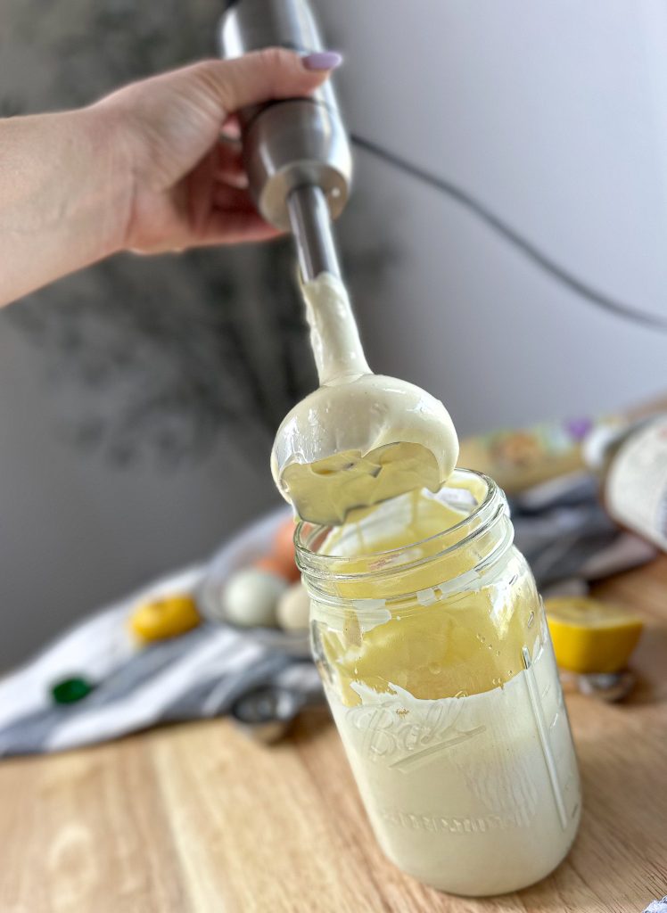 hand holding an emersion blender after whipping mayonnaise in a mason jar