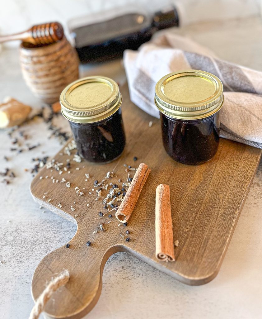 canned elderberry syrup on a wooden board with cinnamon sticks
