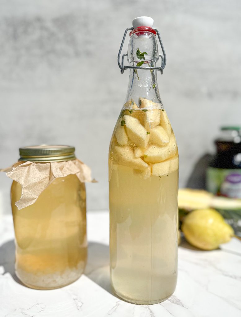 How to make water kefir fermented fruit juice. Water kefir in a jar fermenting and fermented fruit juice in a tall jug.