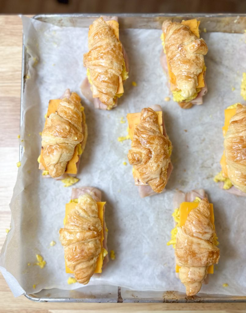 breakfast ham and cheese croissant sandwich on a baking sheet lined with parchment paper