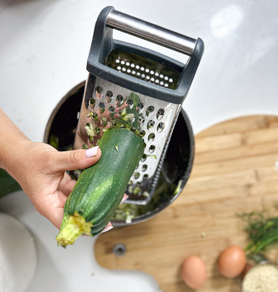 hand grating a zucchini using a grater