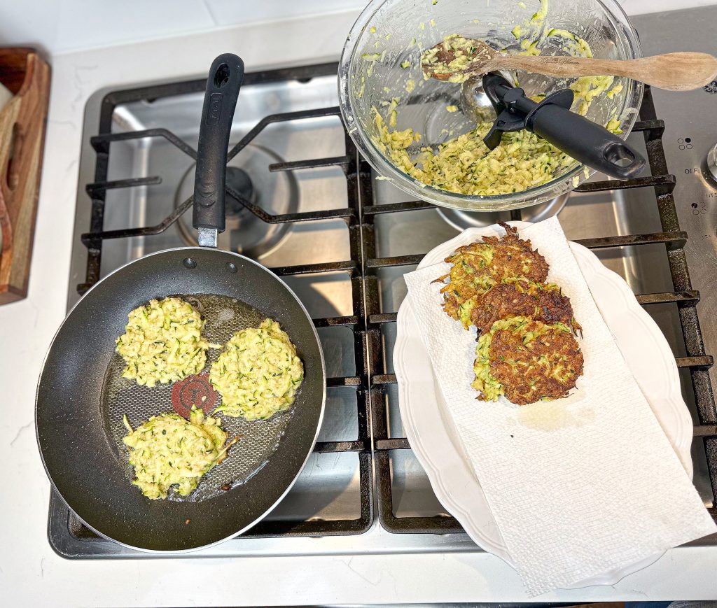 zucchini fritters frying in a pan 
