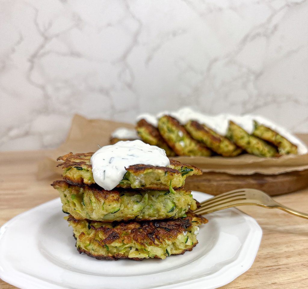 The best sauce to serve with zucchini fritters in a white plate with a gold fork