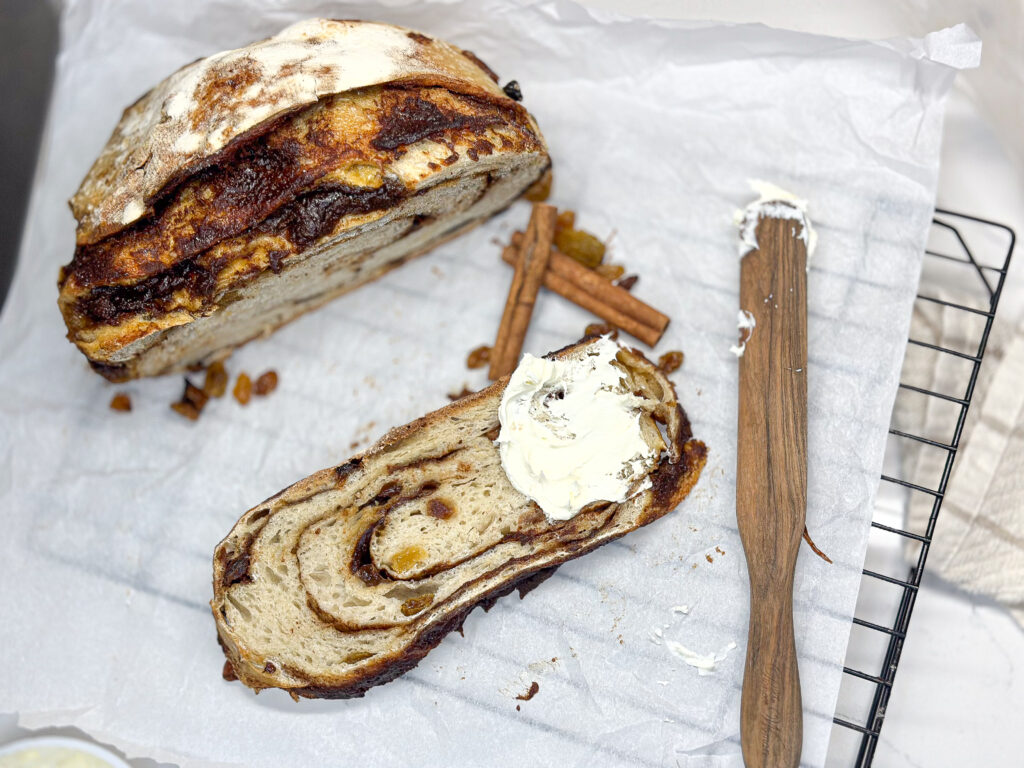 sourdough cinnamon raisin bread sliced on a cooling rack lined with parchment paper 