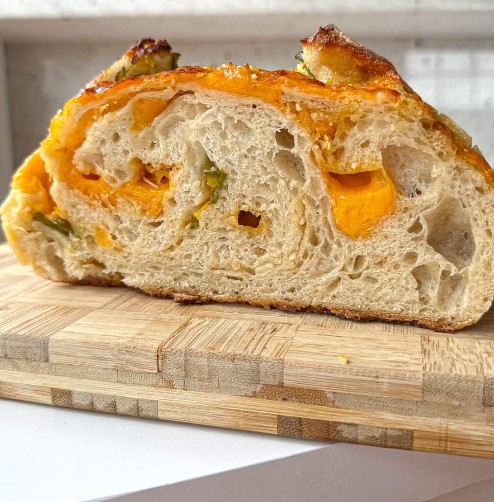 cheddar jalapeno sourdough bread cut in half on a wooden board