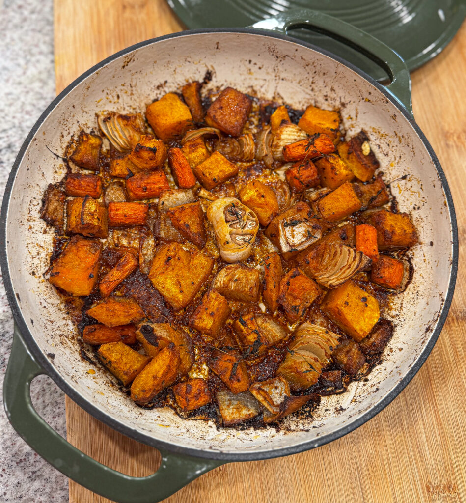 Perfectly roasted butternut squash, onion, and garlic in a Dutch oven after baking—golden brown and caramelized with thyme and olive oil.