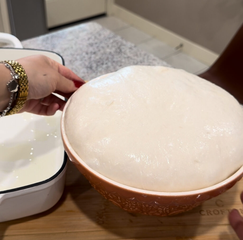 Bowl of sourdough focaccia dough after bulk fermentation, risen tall and puffy, ready to be transferred to the baking pan.