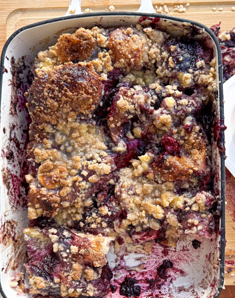 Freshly baked blueberry sourdough focaccia Danish in a white pan, topped with golden brown crumb streusel and jammy blueberry filling.