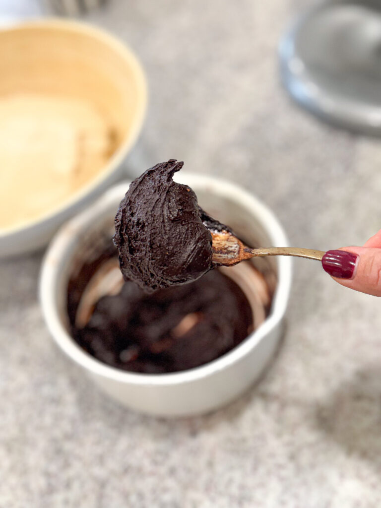 A spoonful of thick homemade chocolate filling made with cocoa, butter, and chocolate chips, ready to spread onto the rolled dough
