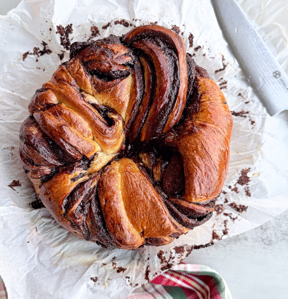 A beautifully baked sourdough chocolate babka wreath with deep golden layers and shiny chocolate ribbons