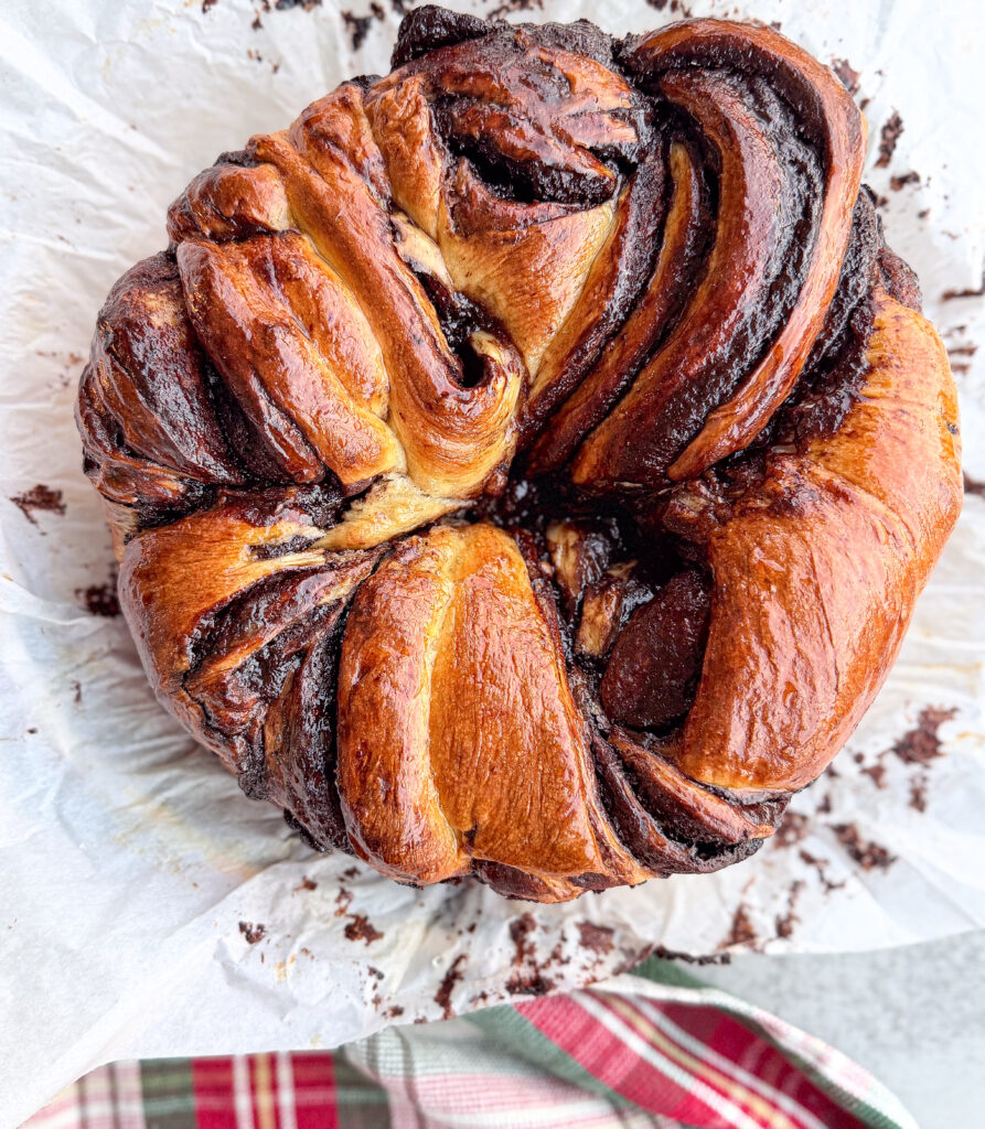 A beautifully baked sourdough chocolate babka wreath with deep golden layers and shiny chocolate ribbons