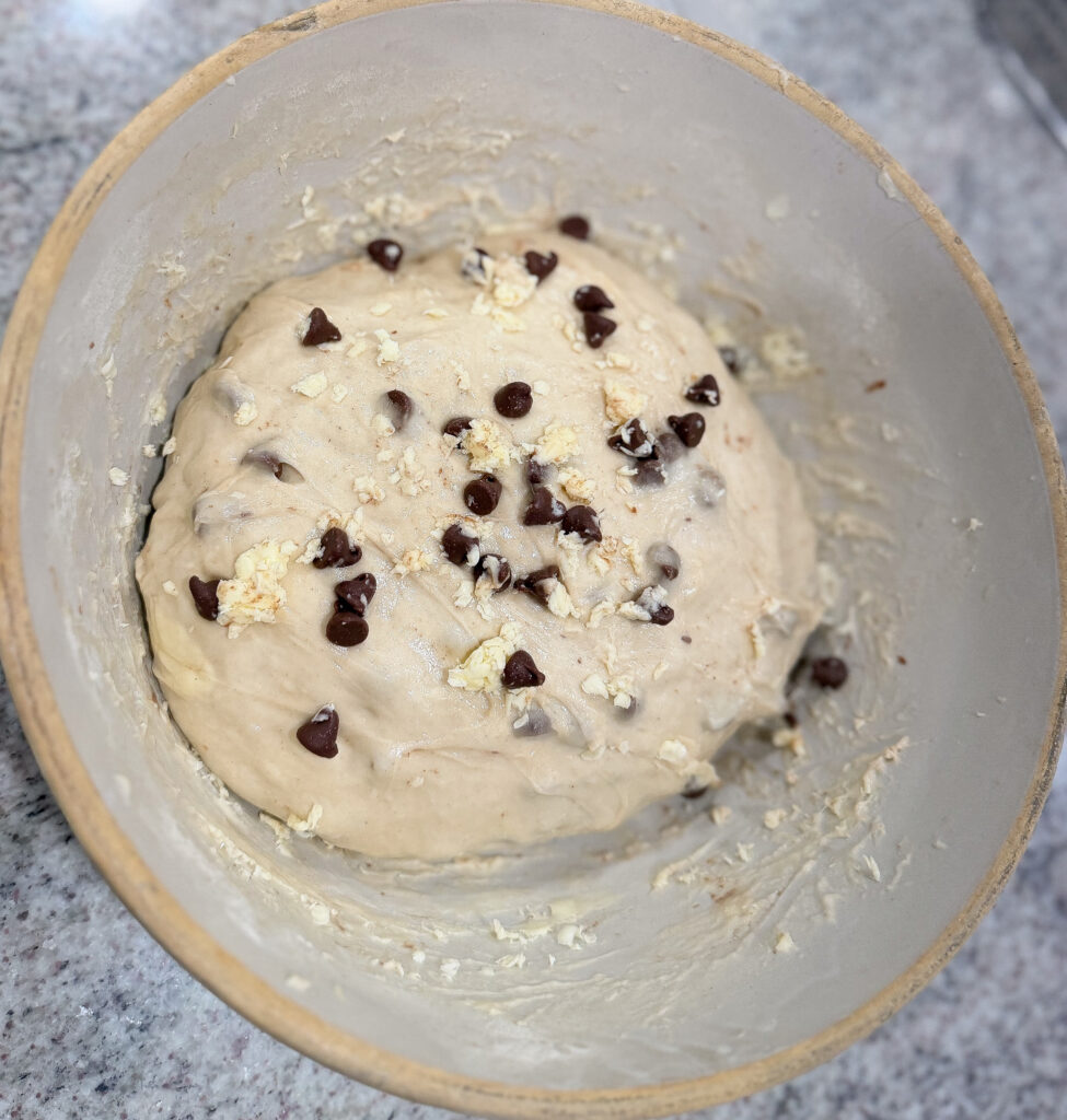 A bowl of sourdough croissant bread dough mixed with grated butter and mini chocolate chips before folding.