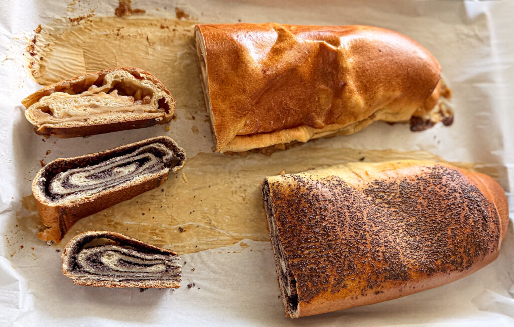 Assorted sliced vertuta rolls with different fillings—poppy seed and apple—displayed on parchment after baking.