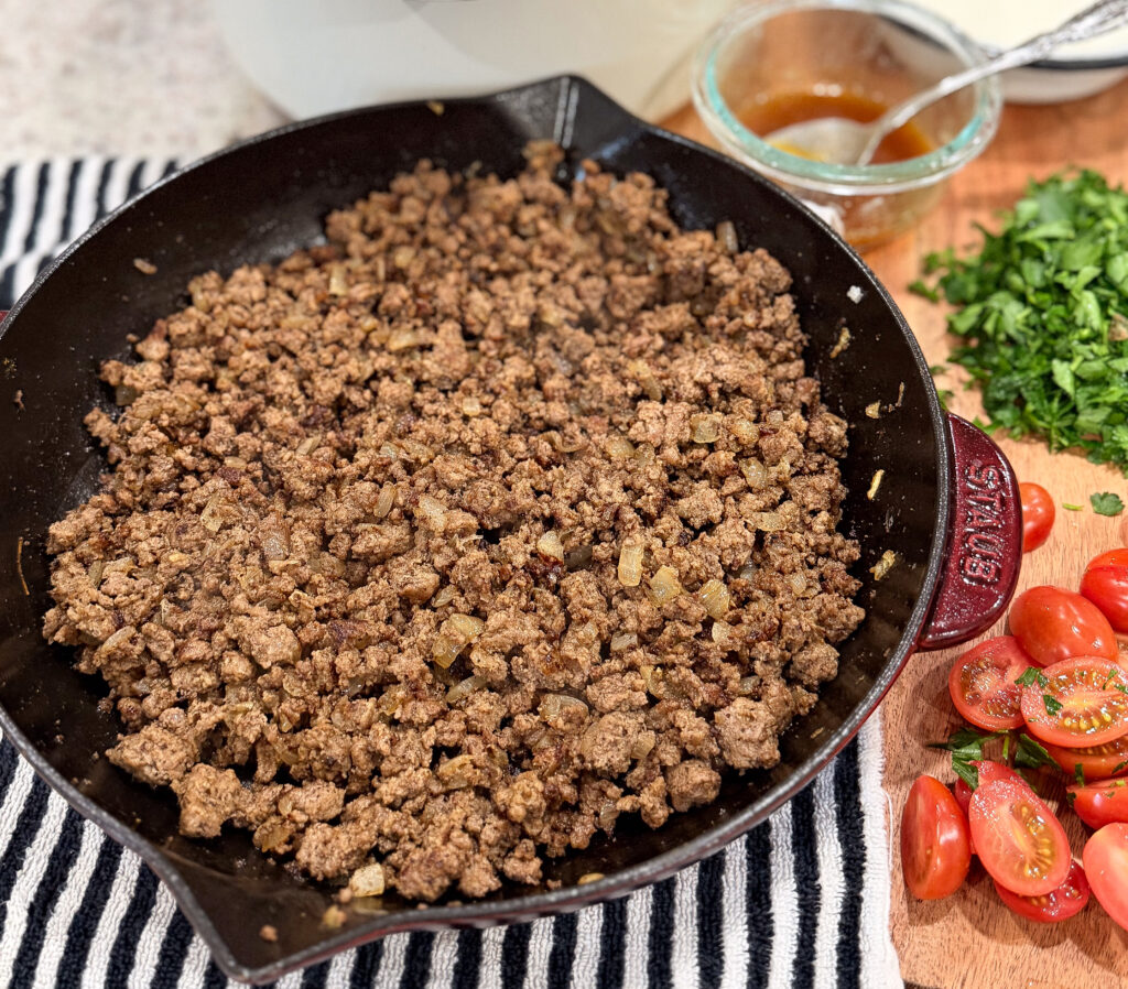: Seasoned ground beef with sautéed onions cooking in a skillet for Turkish pasta recipe