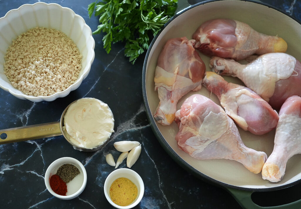 Ingredients: Simple ingredients for air fryer chicken legs including chicken drumsticks, breadcrumbs, mayonnaise, garlic, paprika, seasonings, and fresh parsley.