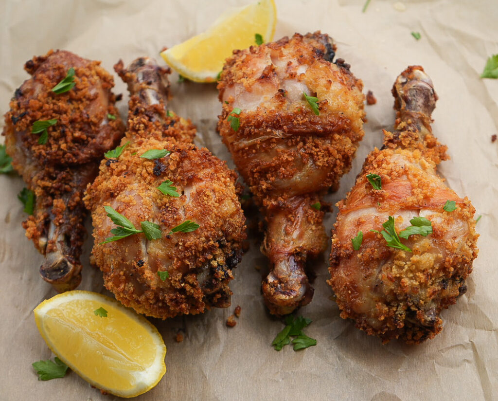 Finished chicken: Crispy air fryer chicken drumsticks cooked until golden brown and juicy, garnished with fresh parsley and lemon wedges.