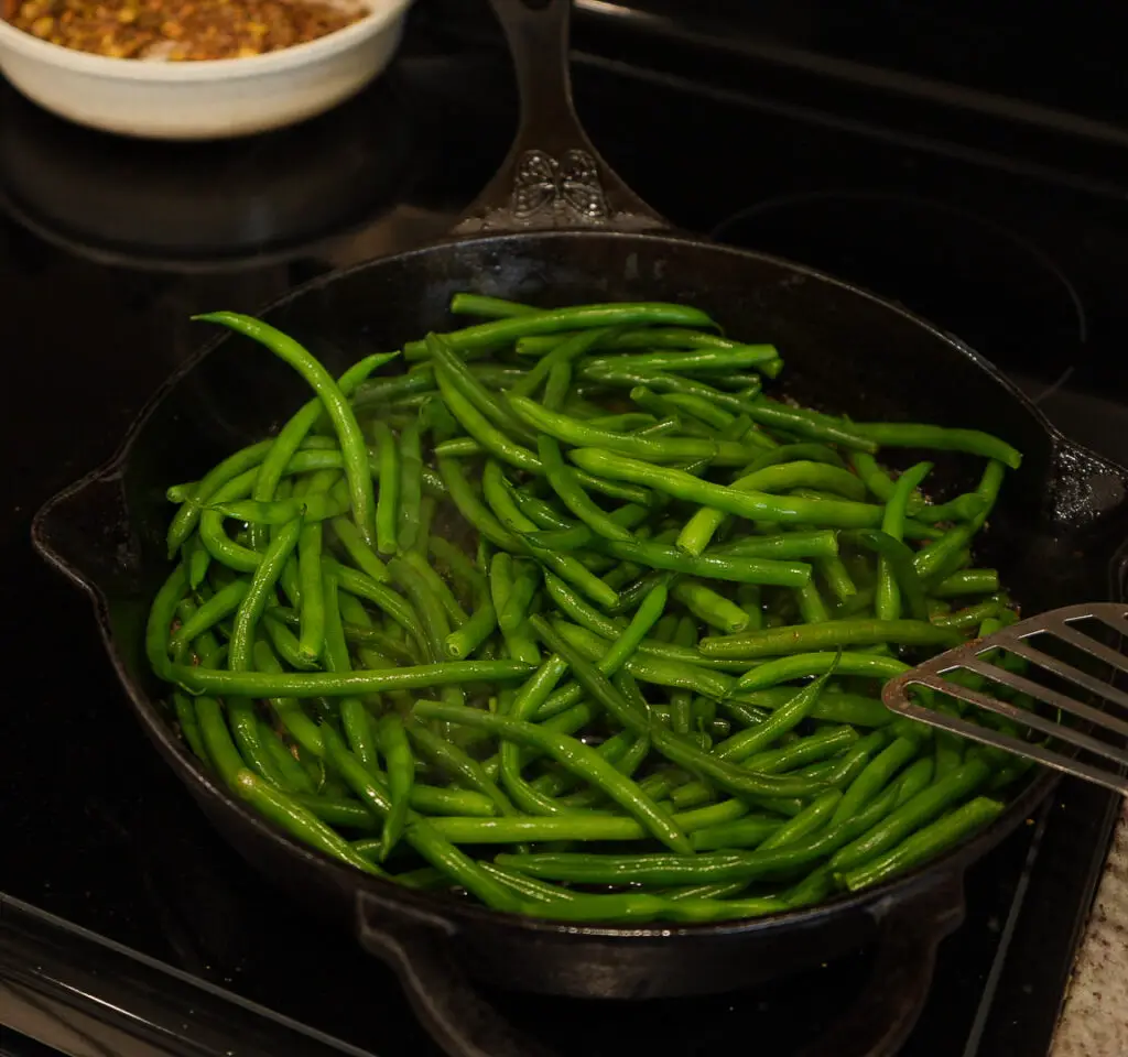Green beans cooking in a cast iron skillet.